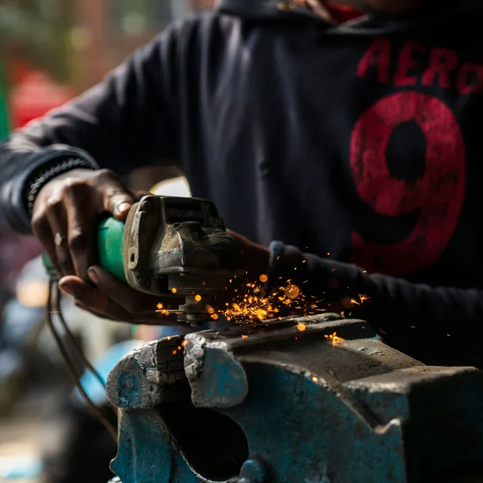 Manos trabajando una pieza en el esmeril del taller